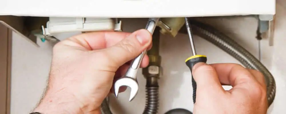 Boiler repair technician tightening pipe fittings and connections in Anaheim, CA