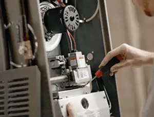 Furnace repair technician inspecting internal components and wiring in Anaheim, CA