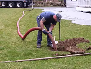 Septic pumping technician servicing a residential septic tank with a vacuum hose in Anaheim, CA
