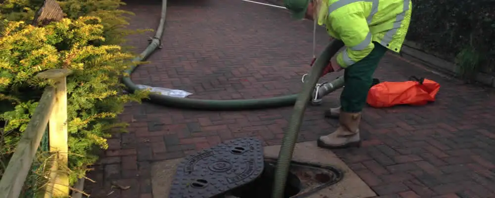 Septic tank cleaning technician servicing a septic tank with a vacuum hose in Anaheim, CA