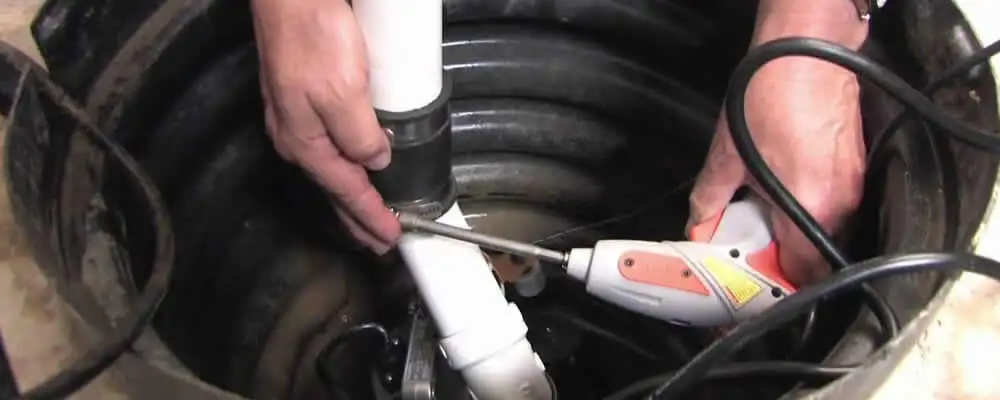 Sump pump installation technician connecting PVC discharge piping in Anaheim, CA